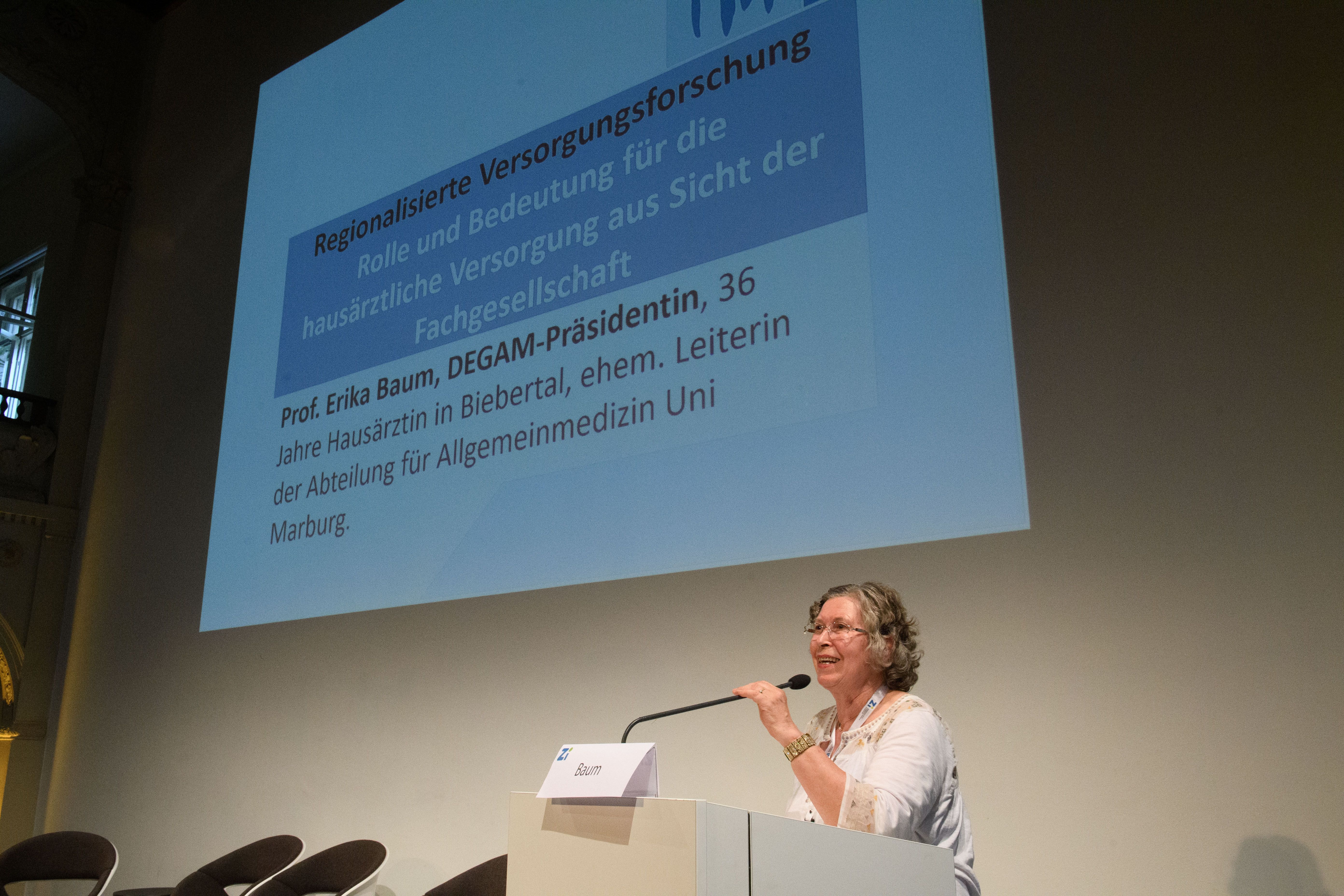 Eine Frau hält einen Vortrag und spricht in ein Mikrofon.
