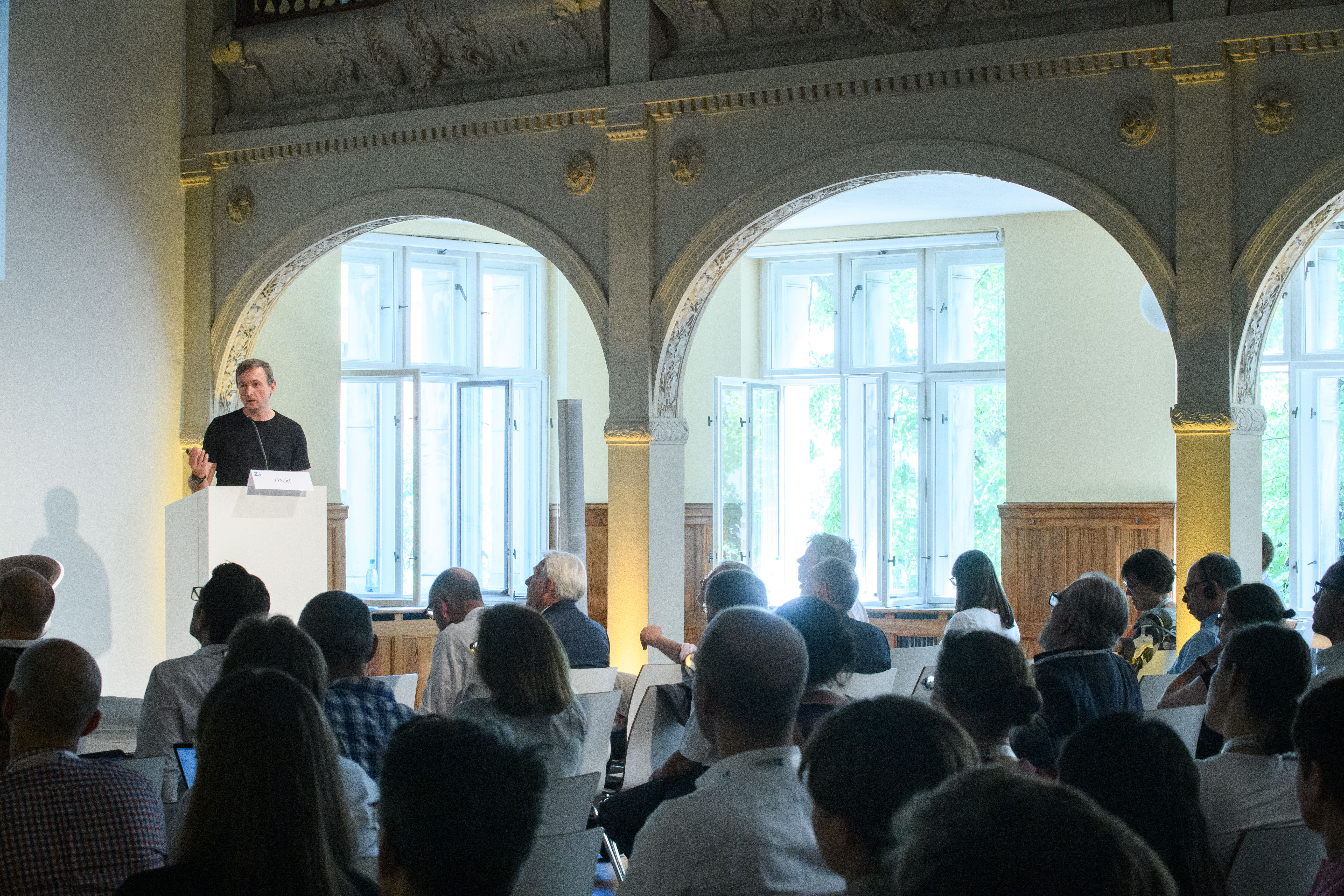 Das Publikum hört dem Vortrag von Herr Hackl zu.